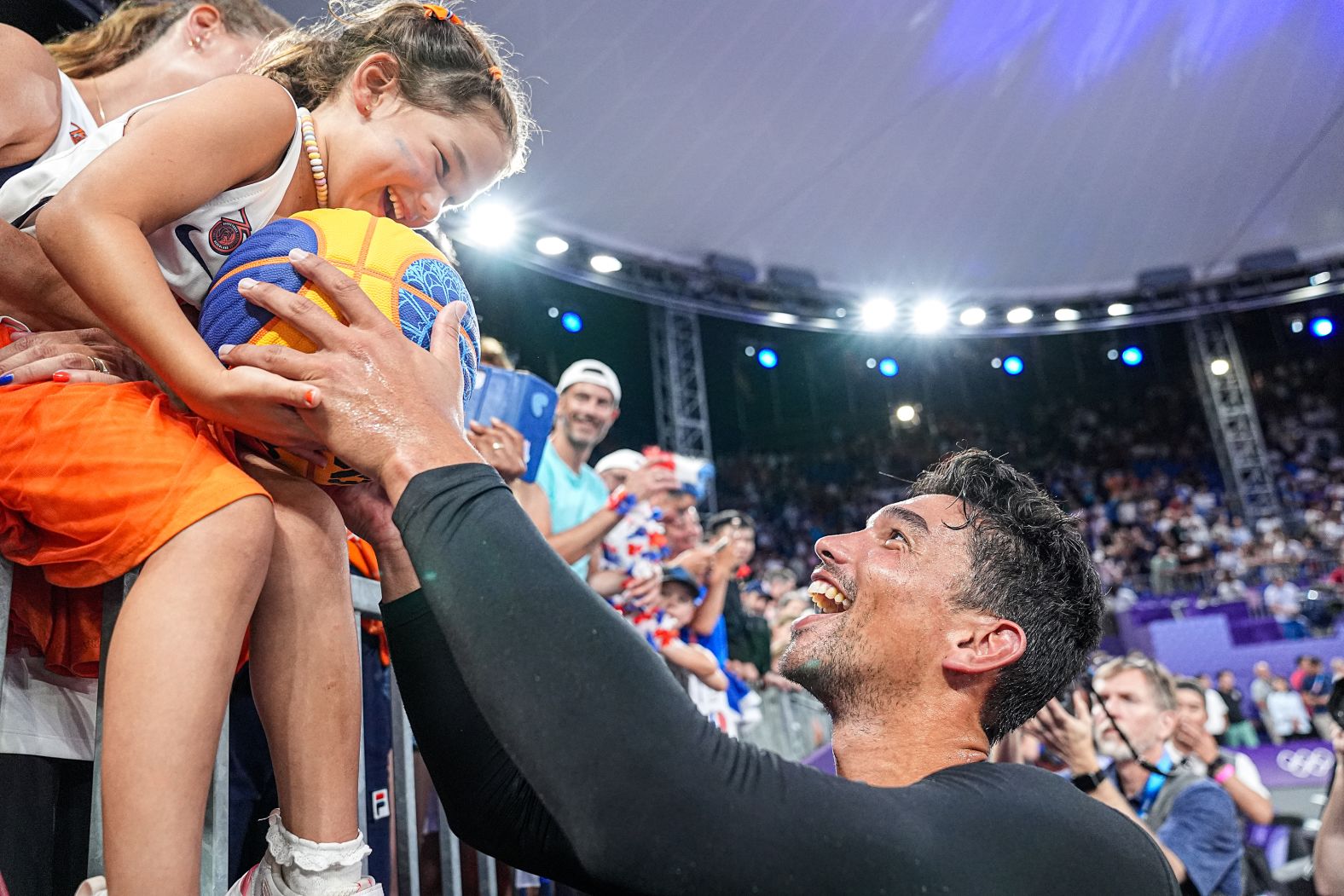 A fan receives a signed ball from Arvin Slagter of the Netherlands after <a href="https://www.cnn.com/sport/live-news/paris-olympics-news-2024-08-05#h_68a38270e283373a1ceb4610dd2412ca">his 3x3 basketball team won gold</a> on August 5.