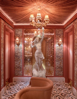 The powder room features pink onyx basins brass wall lights shaped like blossom and pink marble flooring.