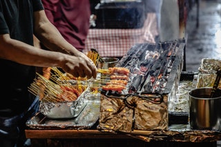 A grill and skewer expert at work on Lau Pa Sat hawker center's famous Satay Street Singapore.