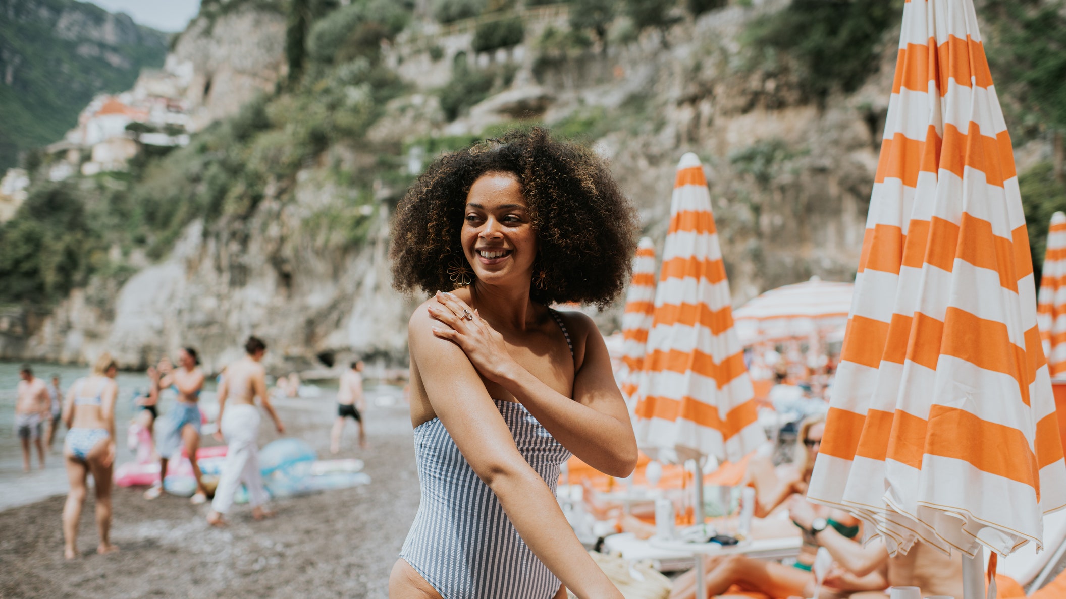 A young woman applies spray suncream on a sunny beach