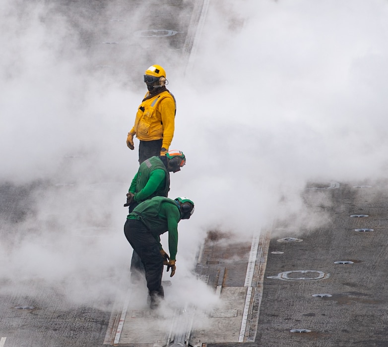 Sailors check a catapult launcher aboard USS Nimitz (CVN 68).