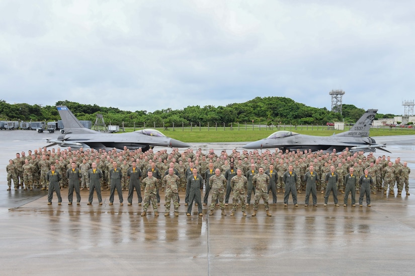 Dozens of airmen and personnel pose in for a photo in front of two parked aircraft.