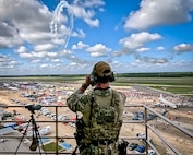 NCIS Agent overlooking air show with binoculars