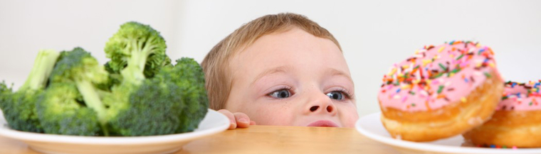 A child choosing between donuts and veggies.