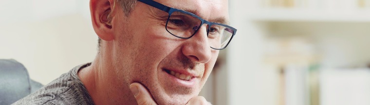 Middle-aged man with hearing aid talking to mobile phone screen. 