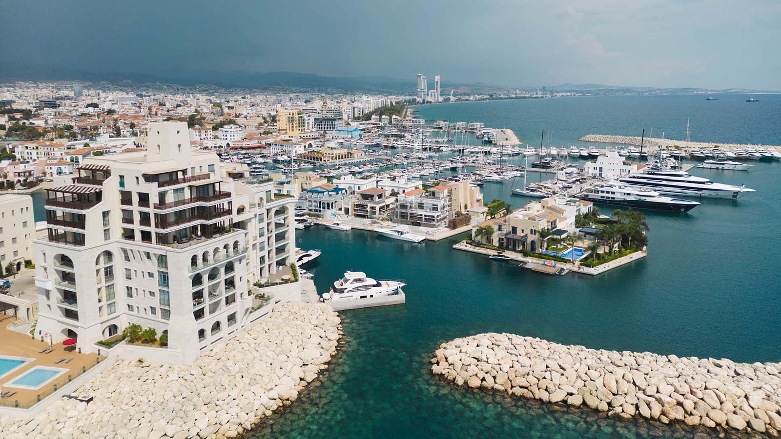 Wide shot overlooking azure coastline and marina full of yachts.