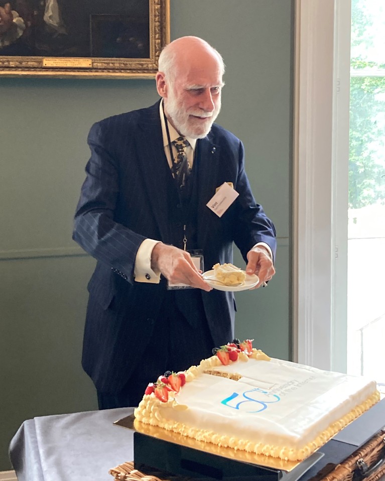 Vint Cerf holds a piece of cake that he just cut at a 50th birthday celebration for the Internet