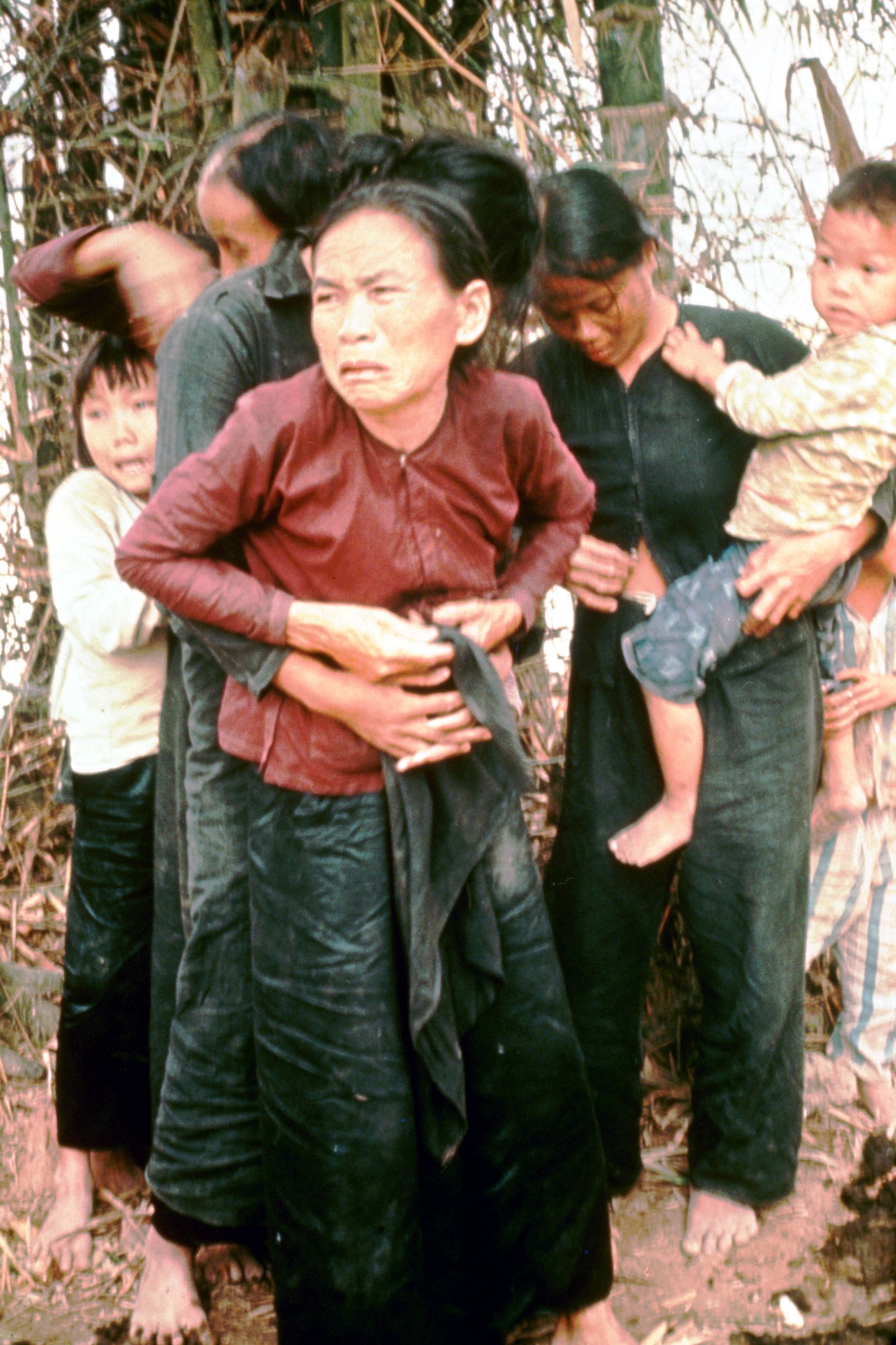 A group of adult and children civilians stand in My Lai embracing each other