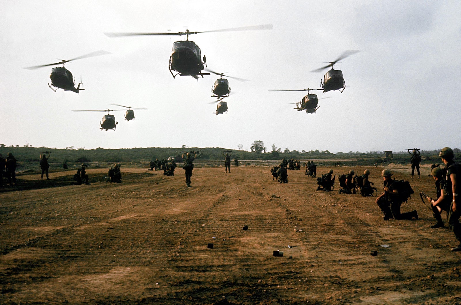 Helicopters landing on a dirt plot in My Lai where soldiers are waiting to board