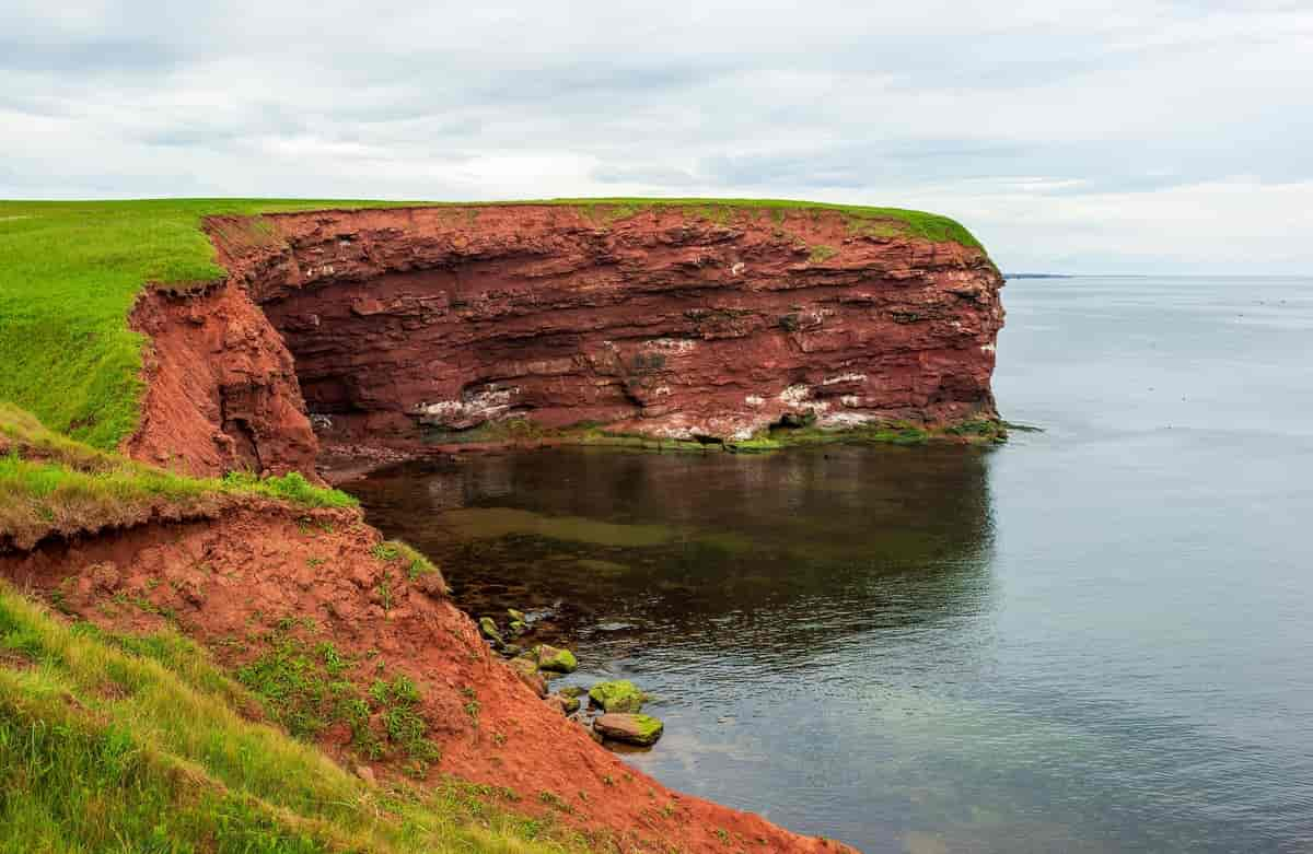 bratte klipper med gress på toppen, sjø nedenfor