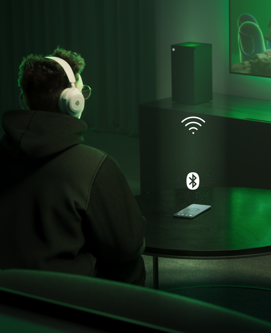 image shows a person playing on a console using headphones connected via bluetooth.