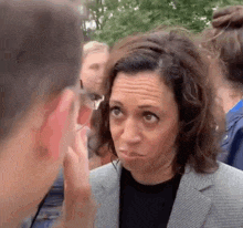 a woman in a suit is talking to a man in a crowd of people .