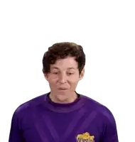 a man is wearing a purple shirt with a yellow logo on it and making a surprised face .