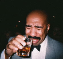 a man with a mustache is crying while drinking from a shot glass