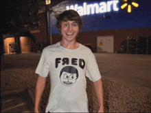 a man wearing a t-shirt that says fred stands in front of a walmart