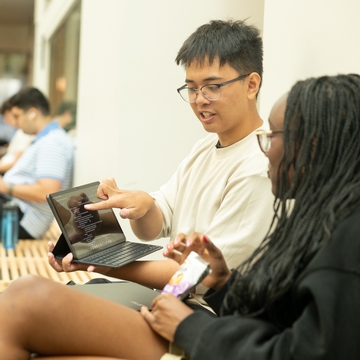 Two students working on a laptop together. 