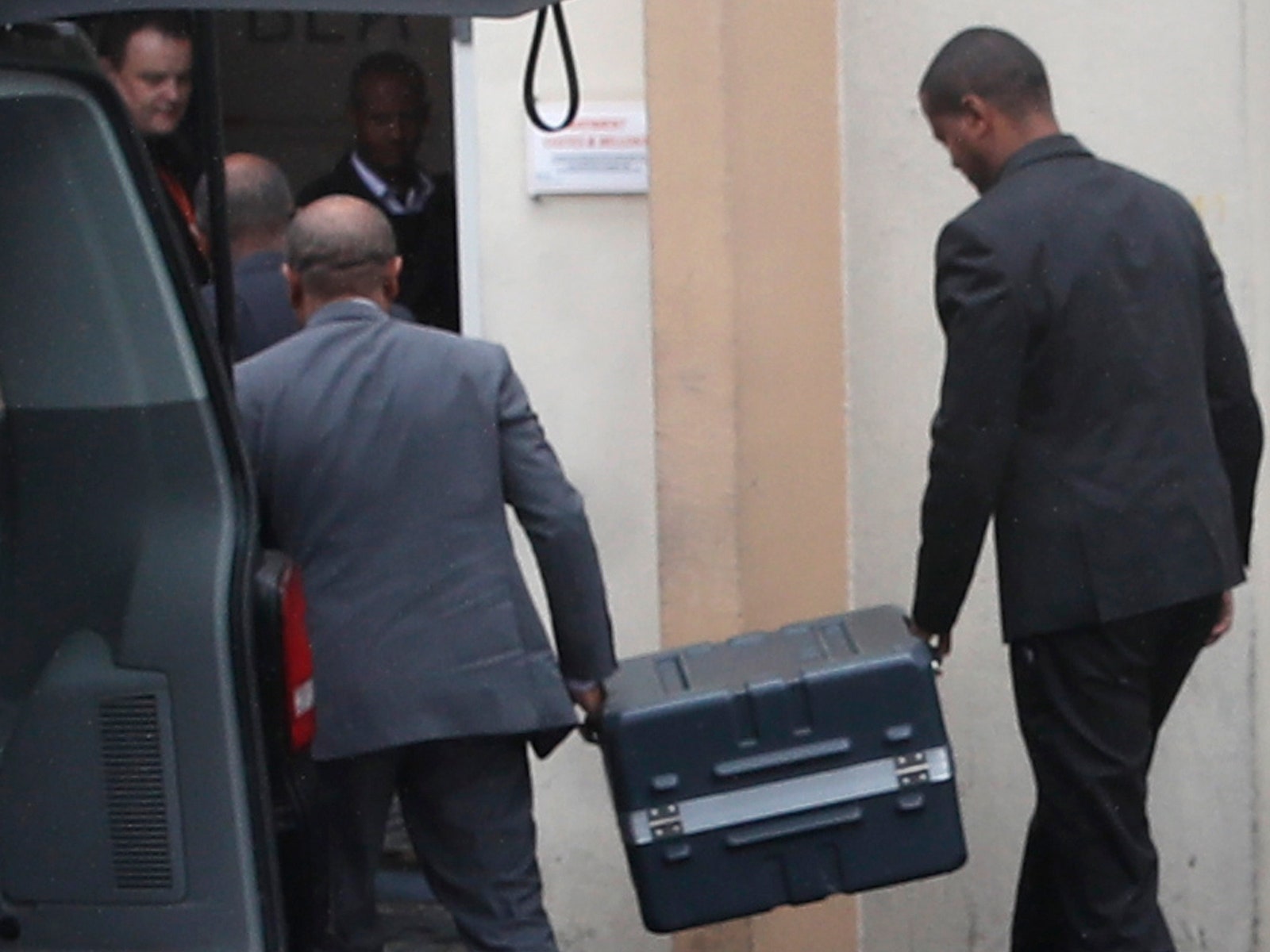 close up view of two men carrying black box from airplane