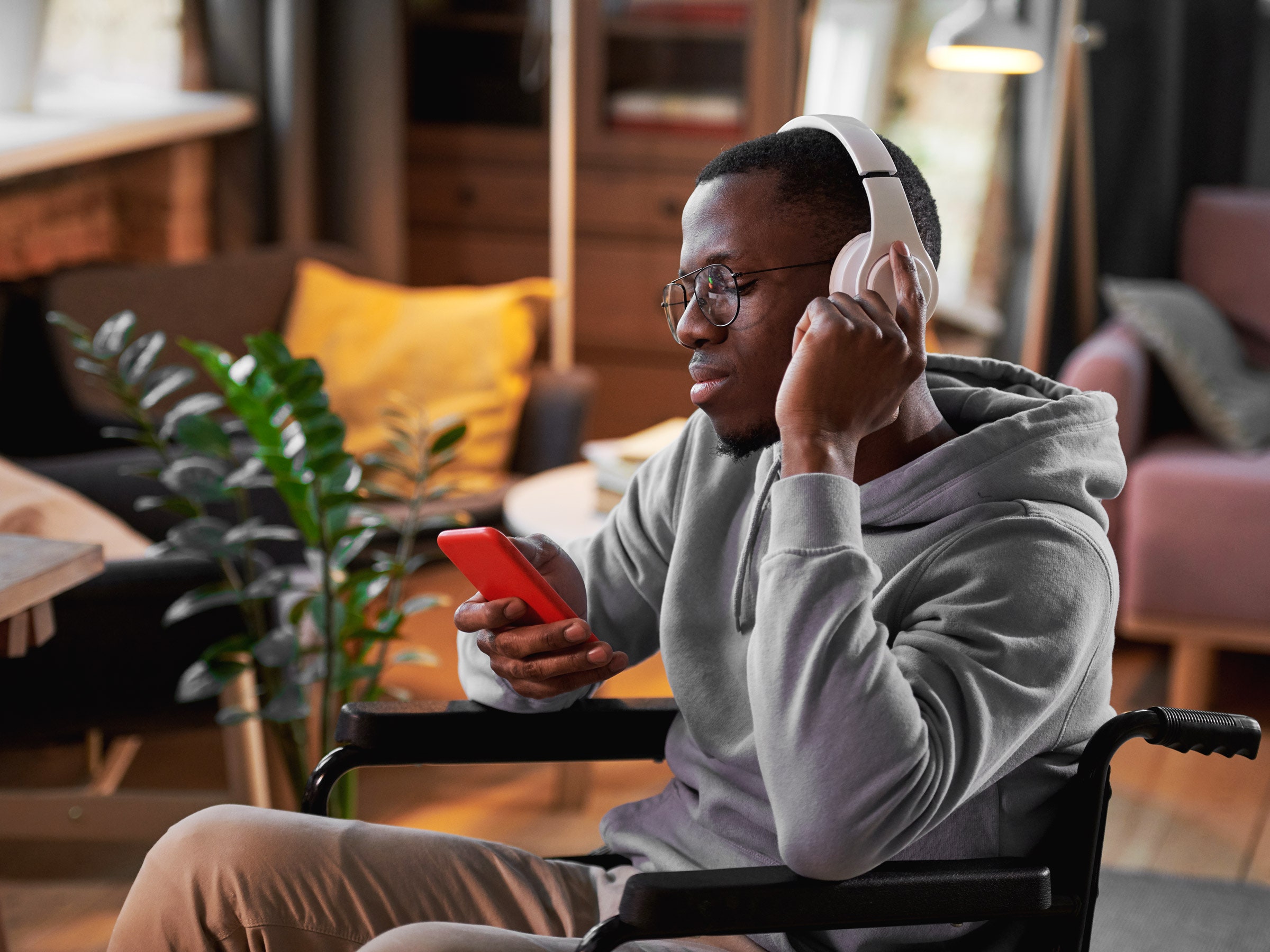 Man in wheelchair listening to music with headphones and phone