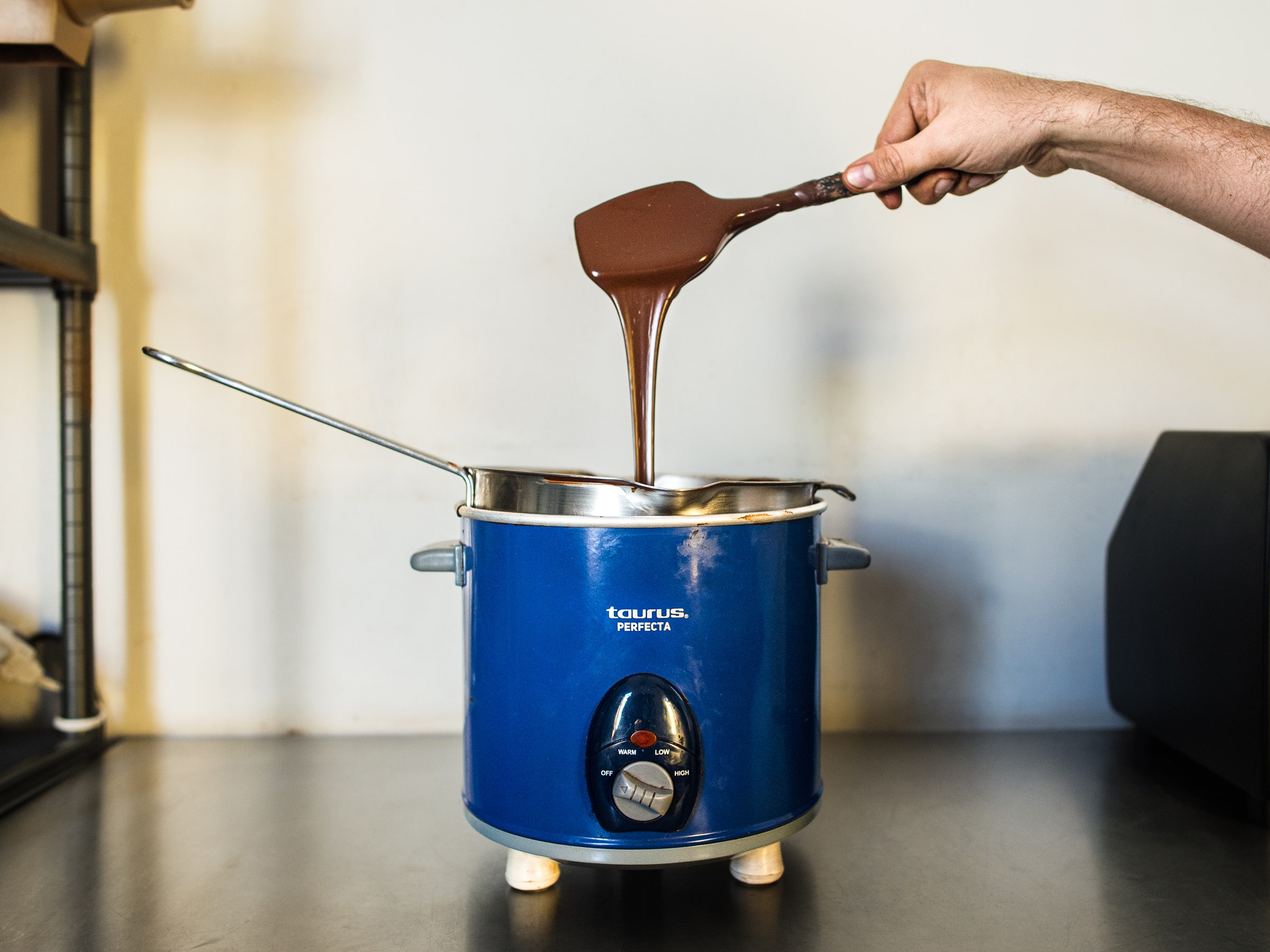 Melted chocolate being spooned into a slowcooker