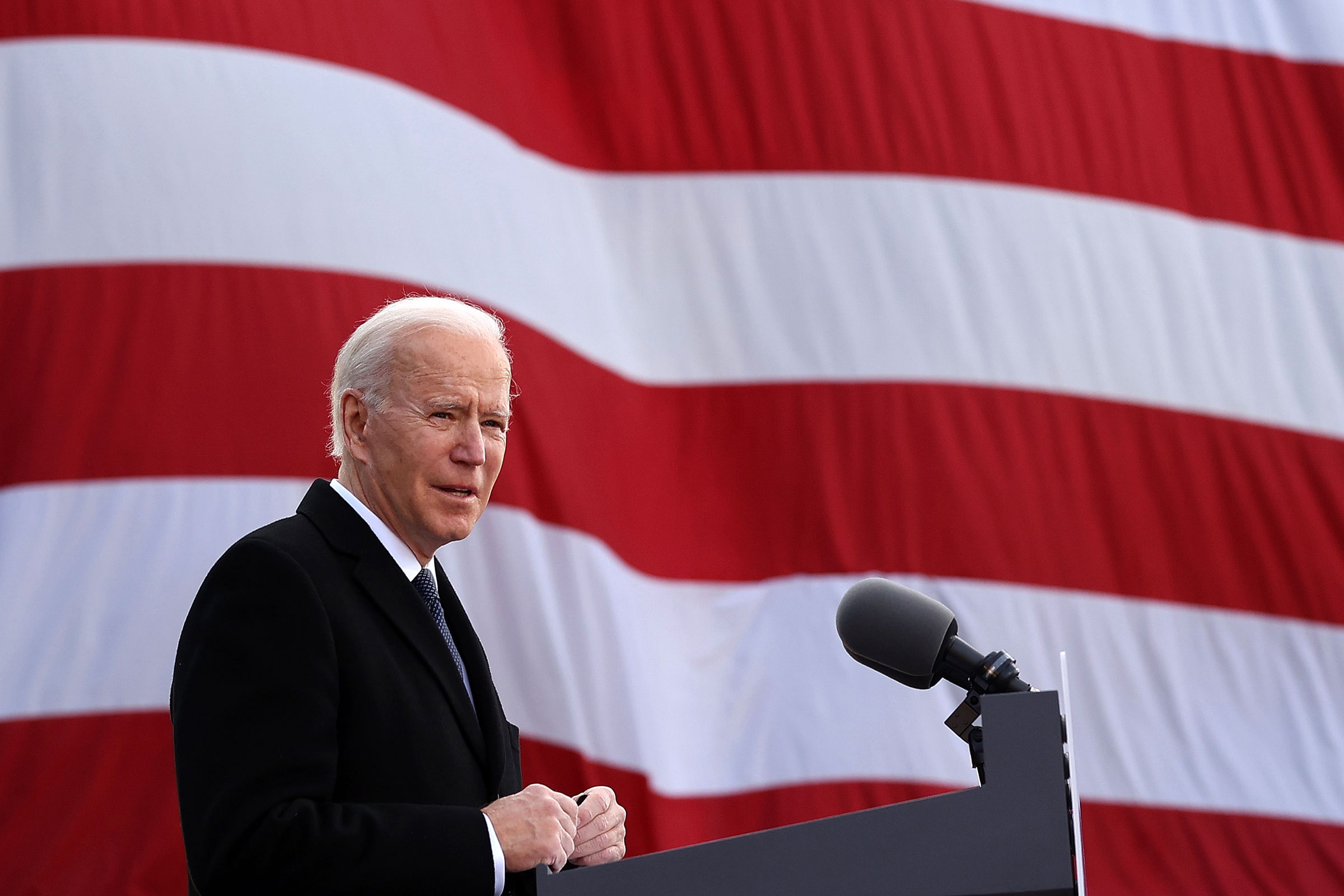 President Biden speaking at podium in front of large American flag