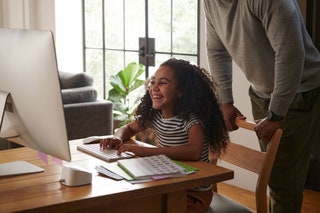 Person and childing working on homework at a computer desk