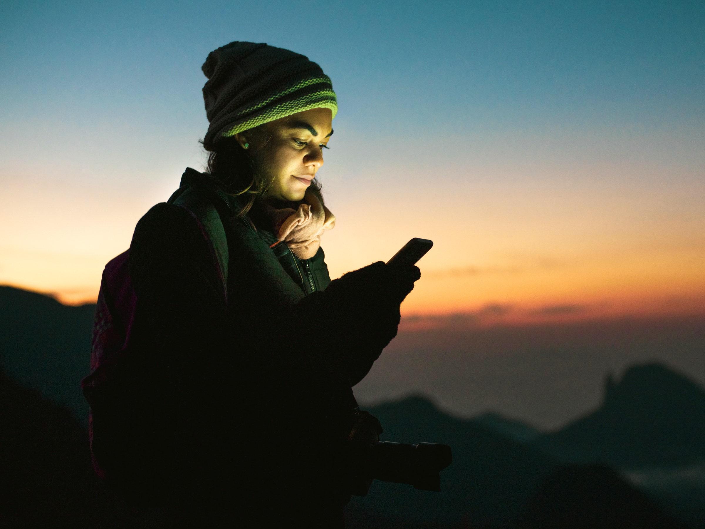 Backpacker using cellphone at mountain peak