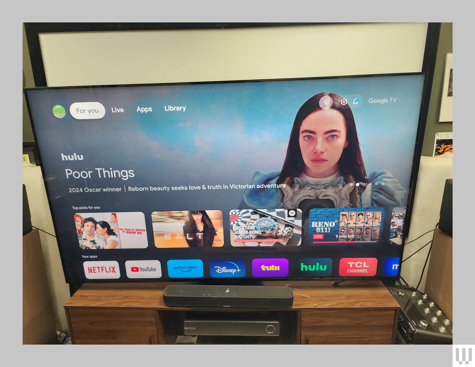 Large flat screen tv on brown credenza showing preview image of a film  video thumbnails and app icons