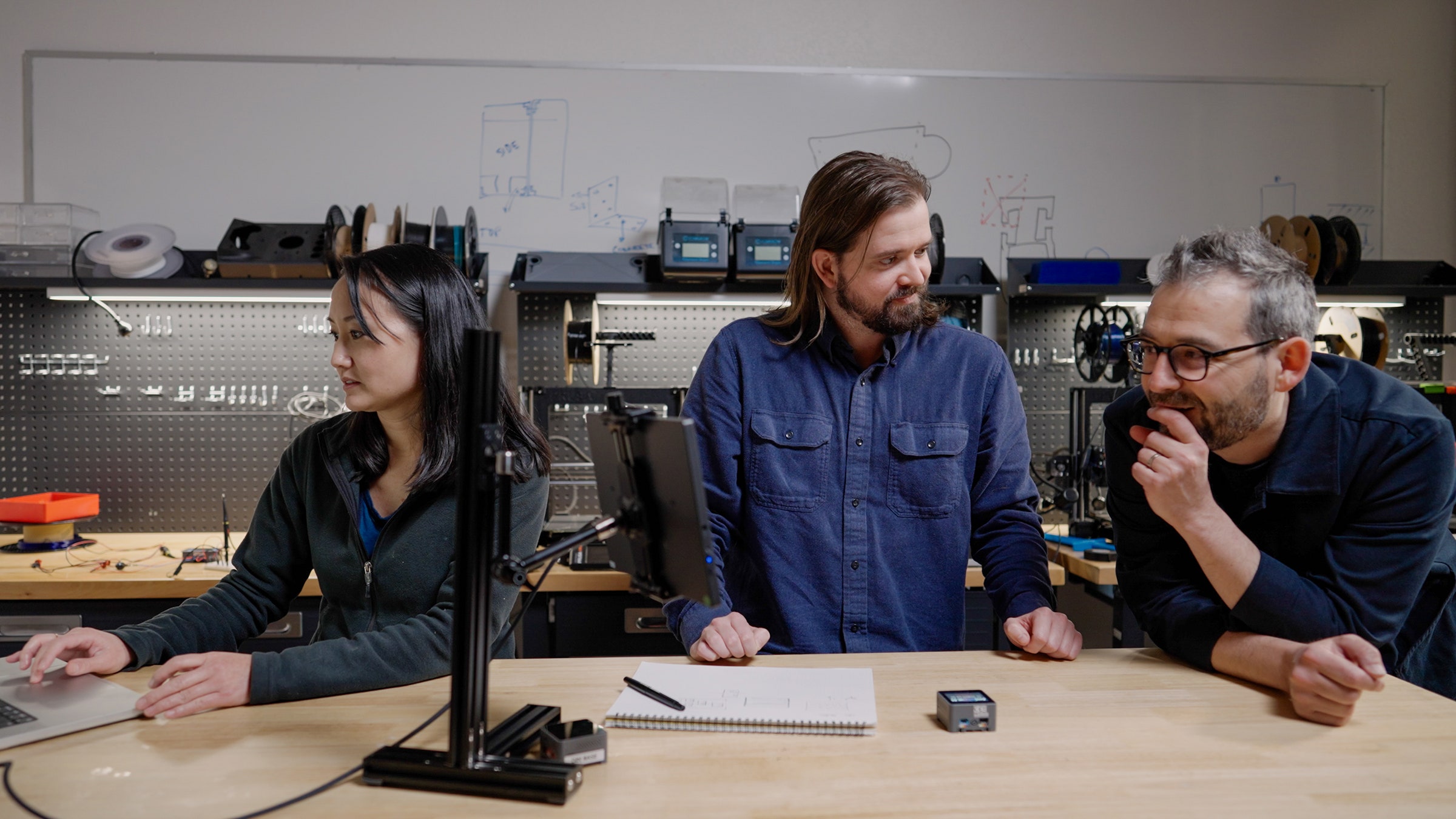 Photo of three people working at a workstation