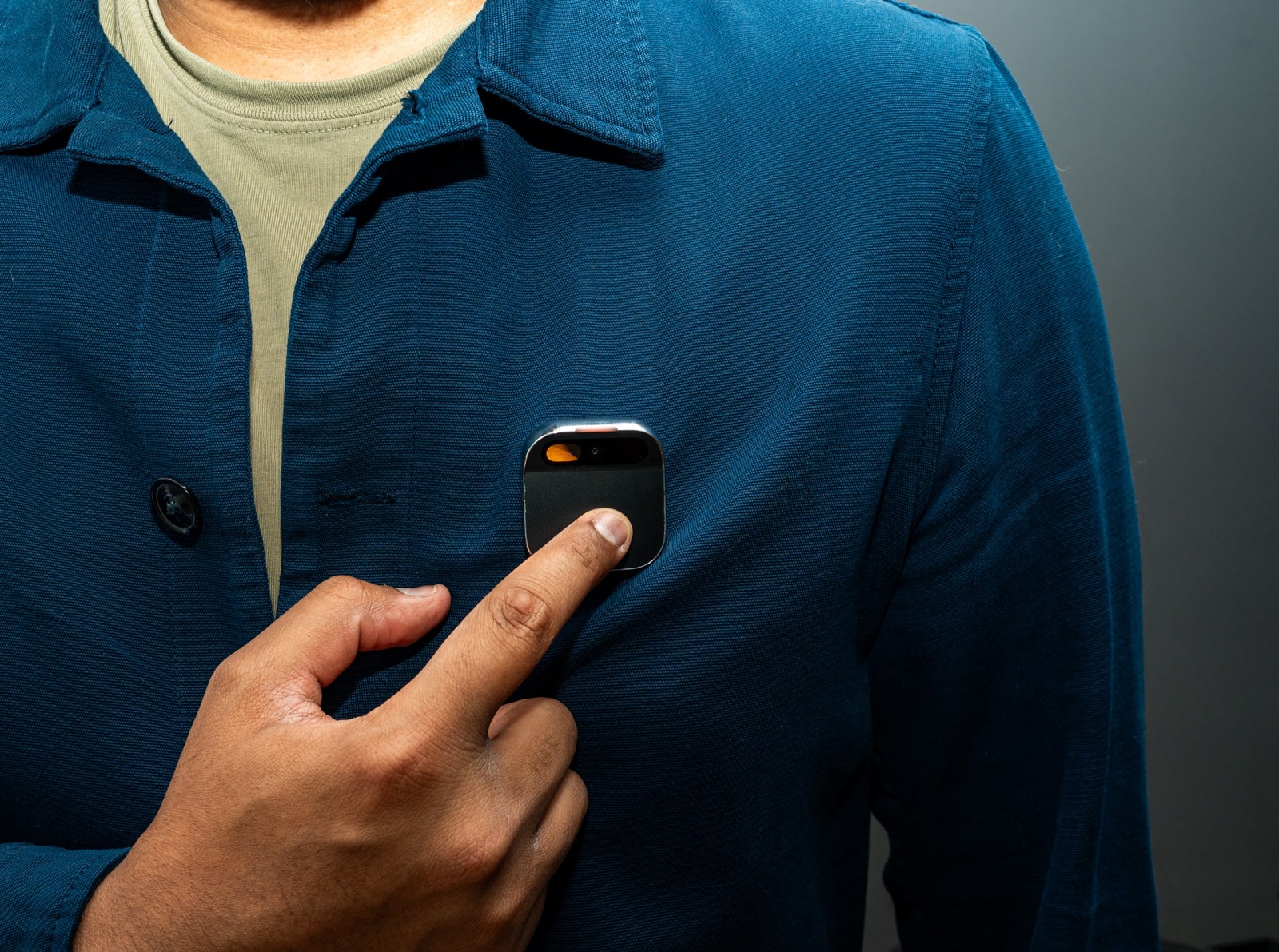 Person touching Humane Ai Pin attached to person's shirt