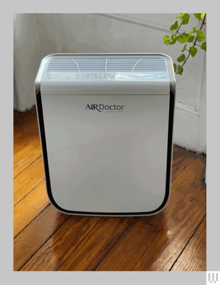 White rectangular device with grated top and black trim sitting on a hardwood floor