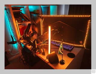 Back view of a desk displaying the back of a monitor illuminated with orange lights