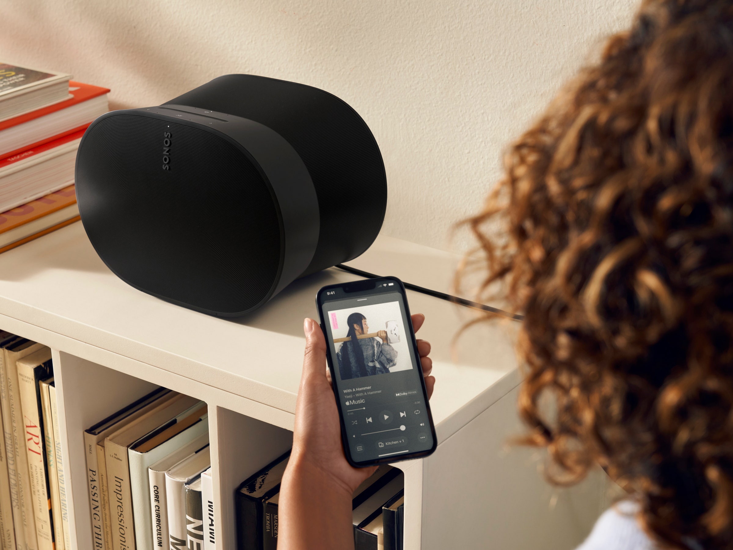 Person using the Sonos app next to a Sonos speaker