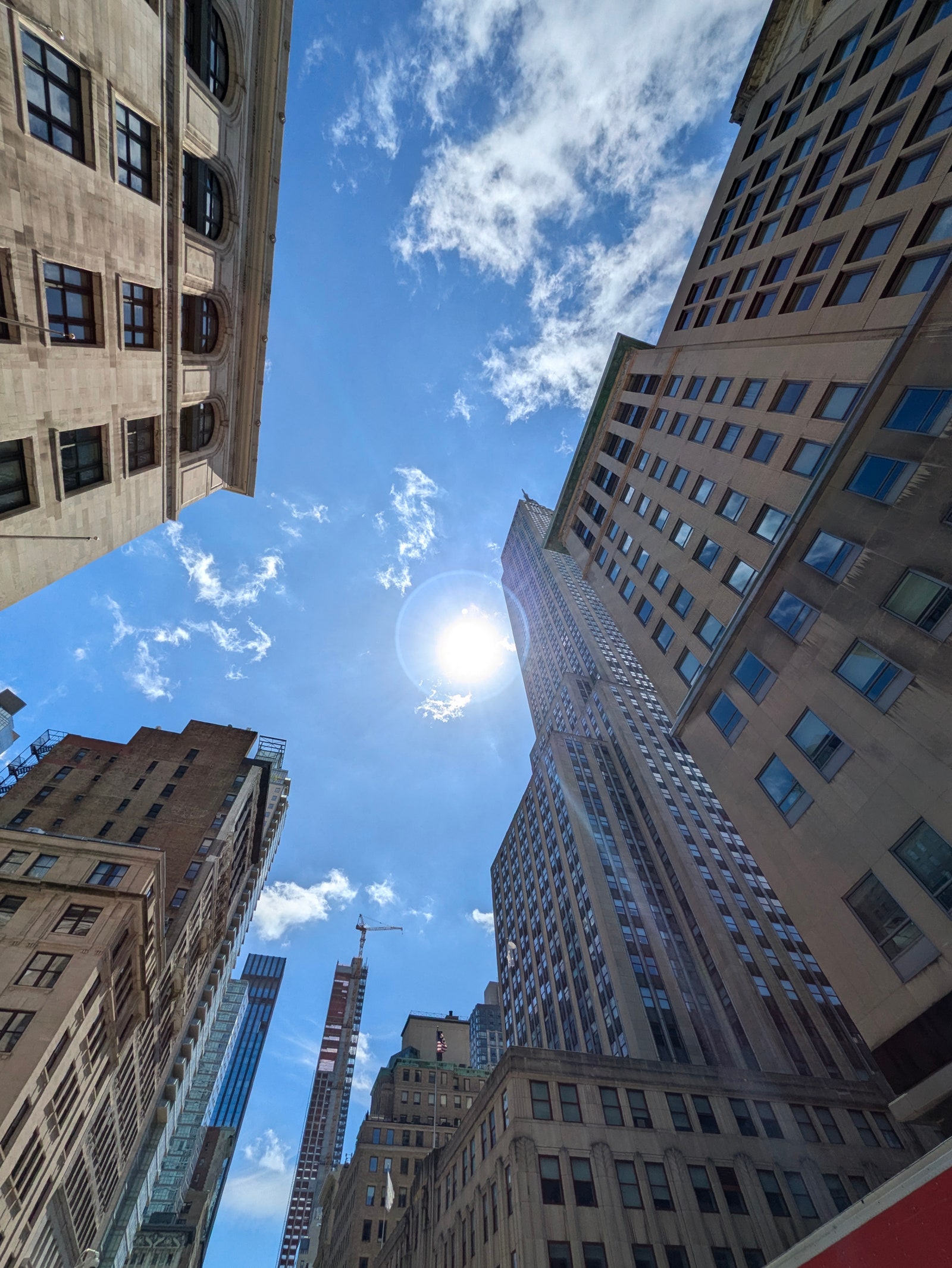 Upward view of a sunny sky with sparse clouds large city buildings on either side