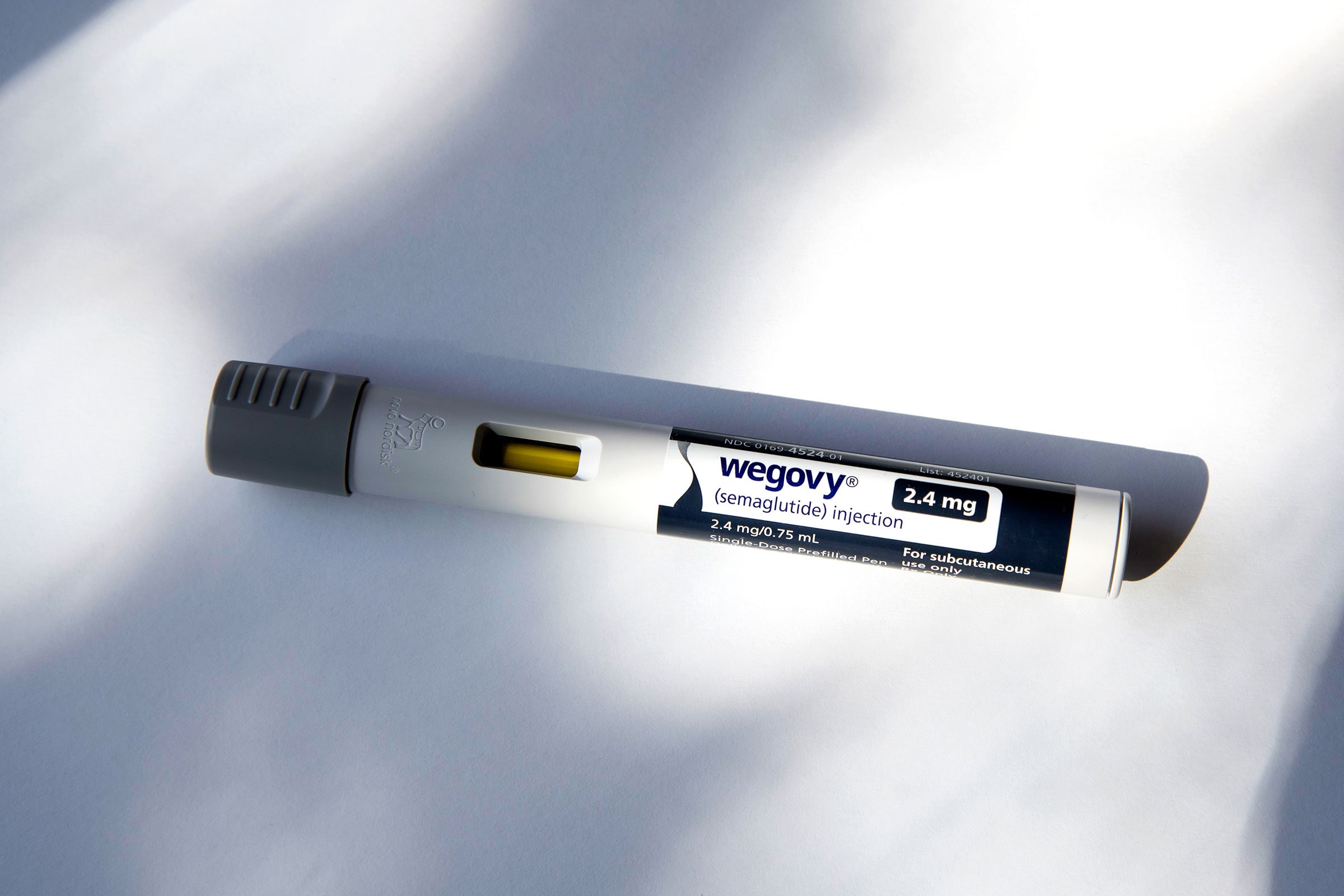 Wegovy injectable prescription weight loss drug on a white surface with dappled lighting