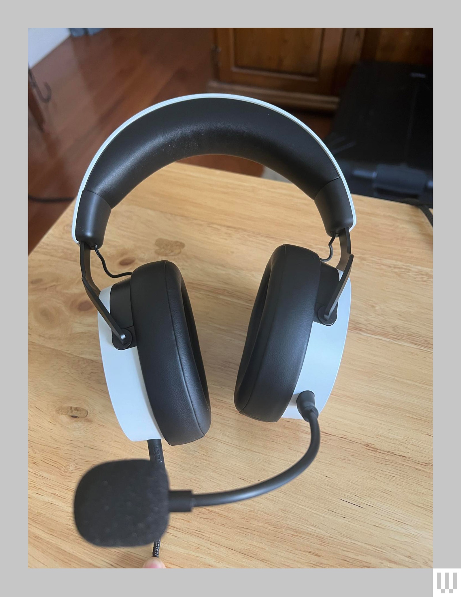 Overhead view of black and white headphones with attached mic sitting on wooden surface