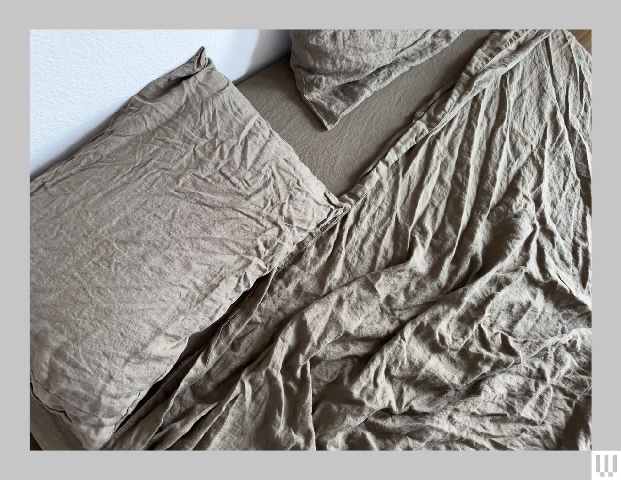 Overhead view of wrinkled grey linen sheets and pillows