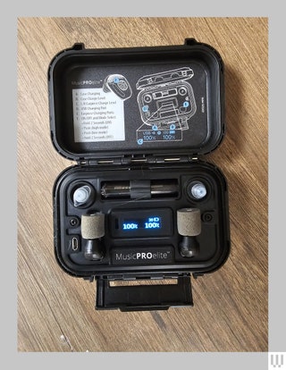 Small black case open to show 2 earplugs accessories and a small digital screen showing the battery percentage