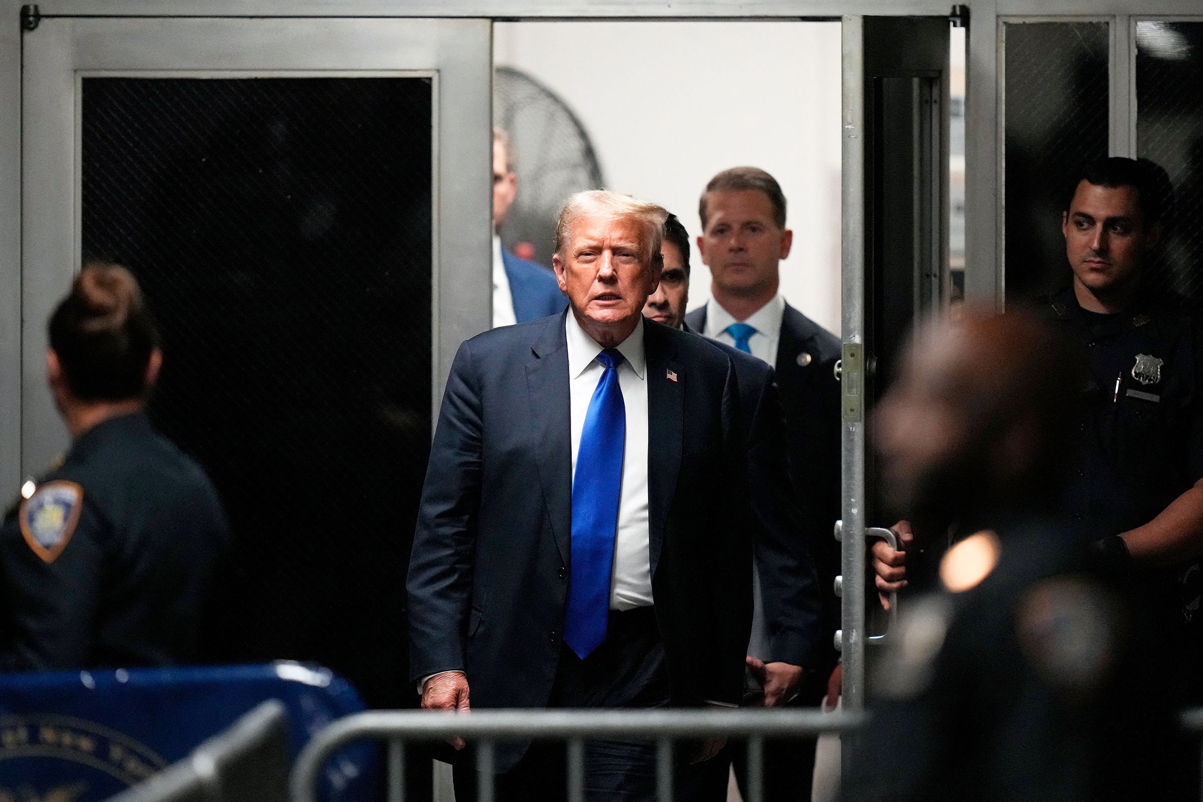 Donald Trump walking through a door with officers and other officials around him