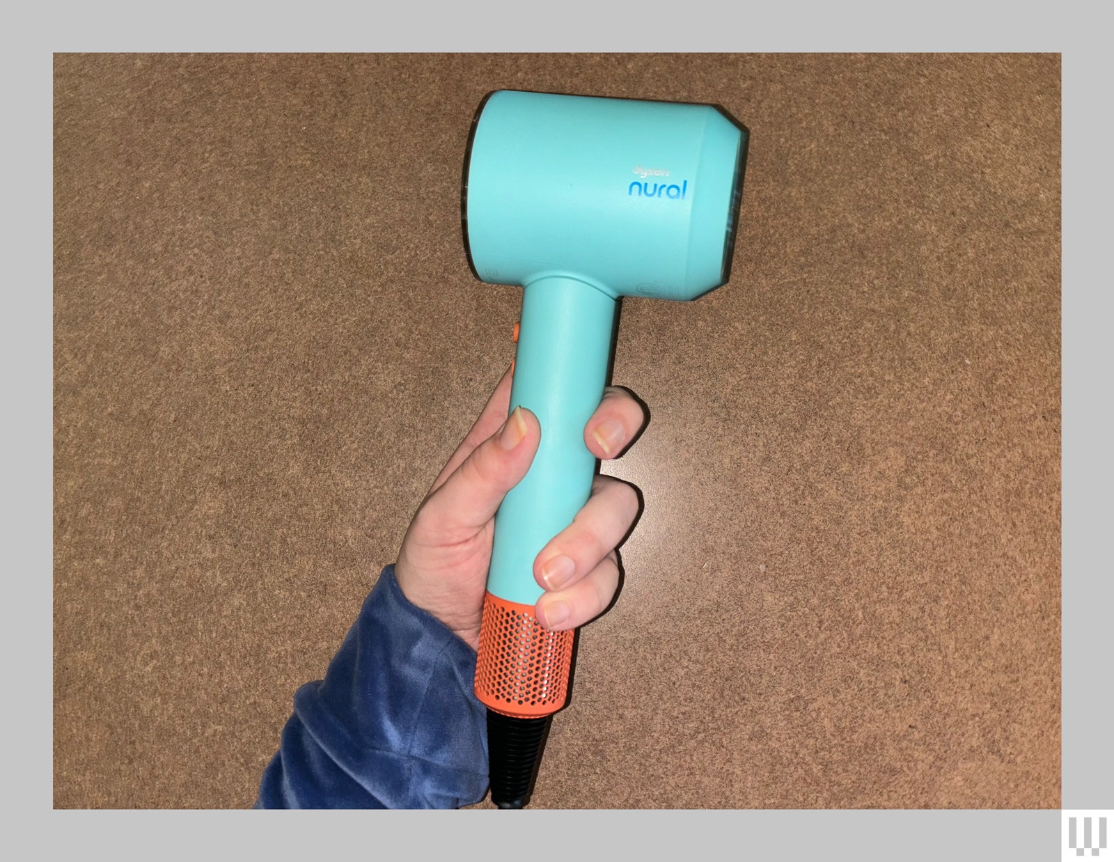 Hand holding small hair dryer with narrow handle and small cylindrical main component