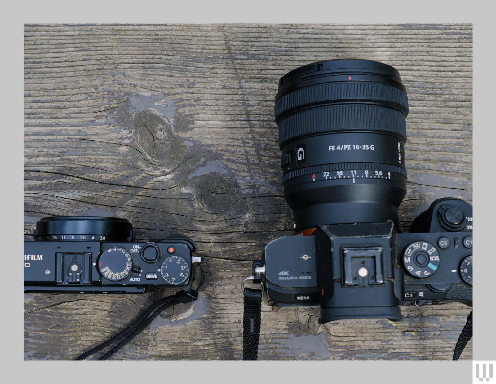 Top view of small black camera beside larger camera with extended lens