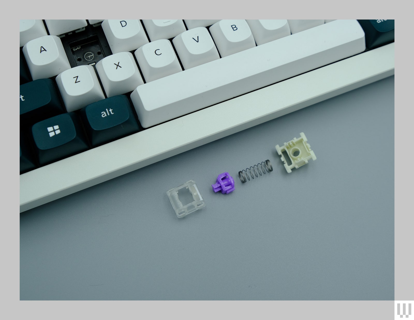 Closeup of a computer keyboard with a few pieces in front of it including a spring clasp and other parts