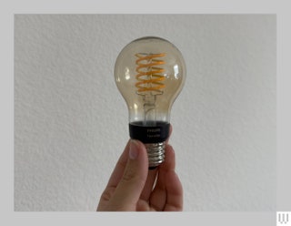 Yellow tinted light bulb with spiral filament inside being pinched by the base and held up