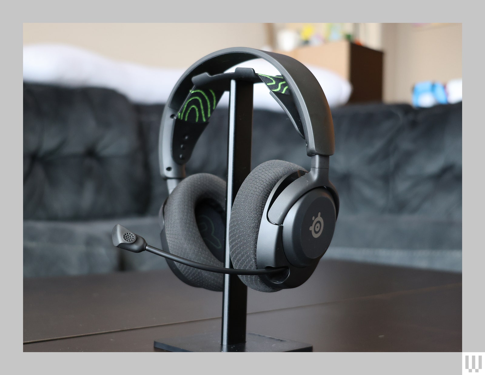 Black headset with cushioned ear cups padded headband and extended mic hooked on a tabletop stand