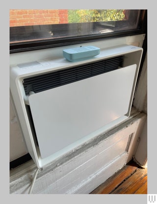 Air conditioner in a window with a teal remote sitting on the top