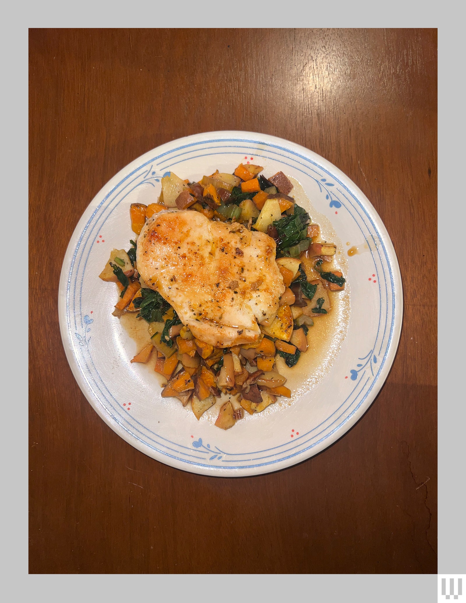 Overhead view of a plated meal of chicken and veggies sitting on a wooden table