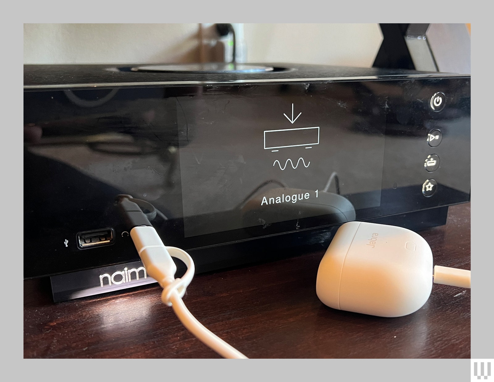 White case plugged into an amp via a white cord allowing the sound of a vinyl record to be played through earbuds