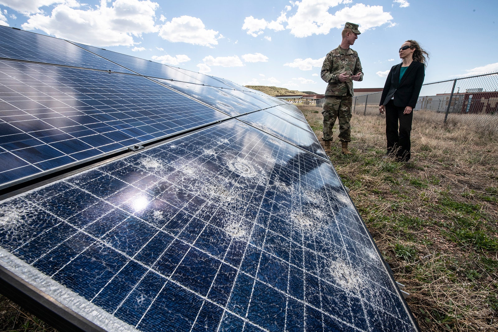Photo of a researcher from the National Renewable Energy Laboratory reviewing hail damage at a solar array at Fort...