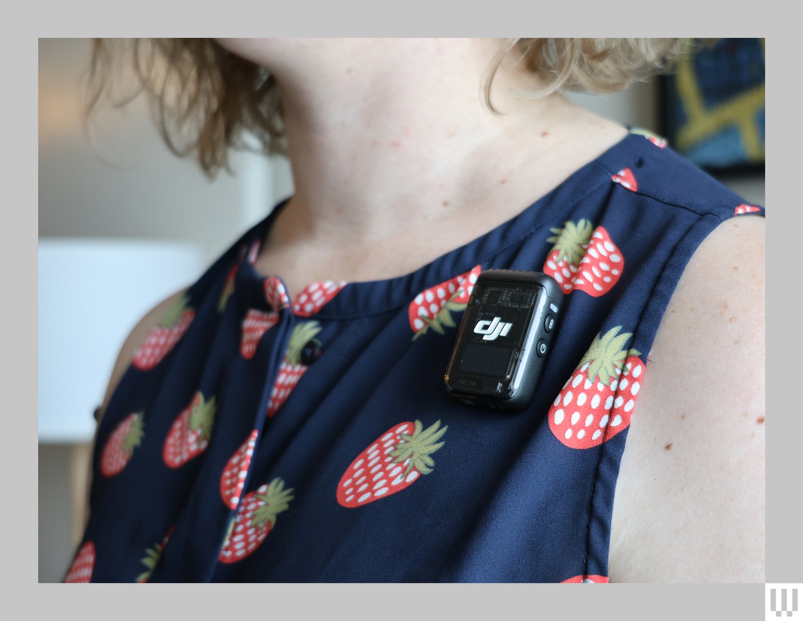 Closeup of a person's strawberry patterned shirt and a clipon mic attached