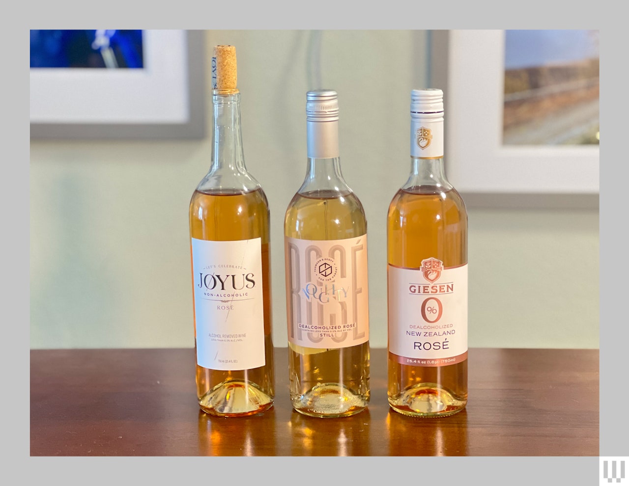 3 bottles of nonalcoholic beverages with light colored liquid inside, sitting on a wooden table