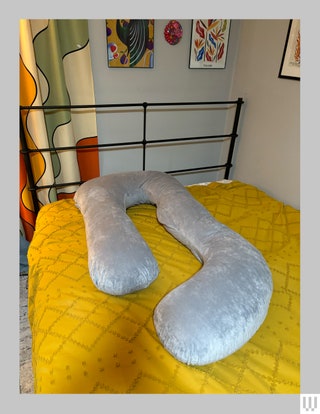 Curvy body pillow on top of a bed with yellow blanket